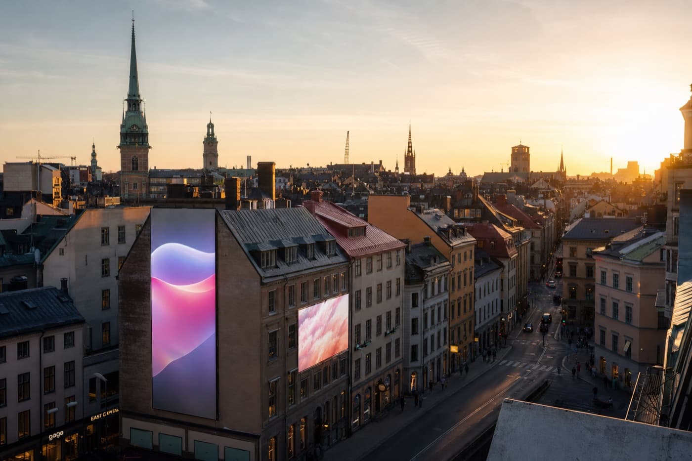Svensk stadssiluett med digitala reklamytor i kvällsljus